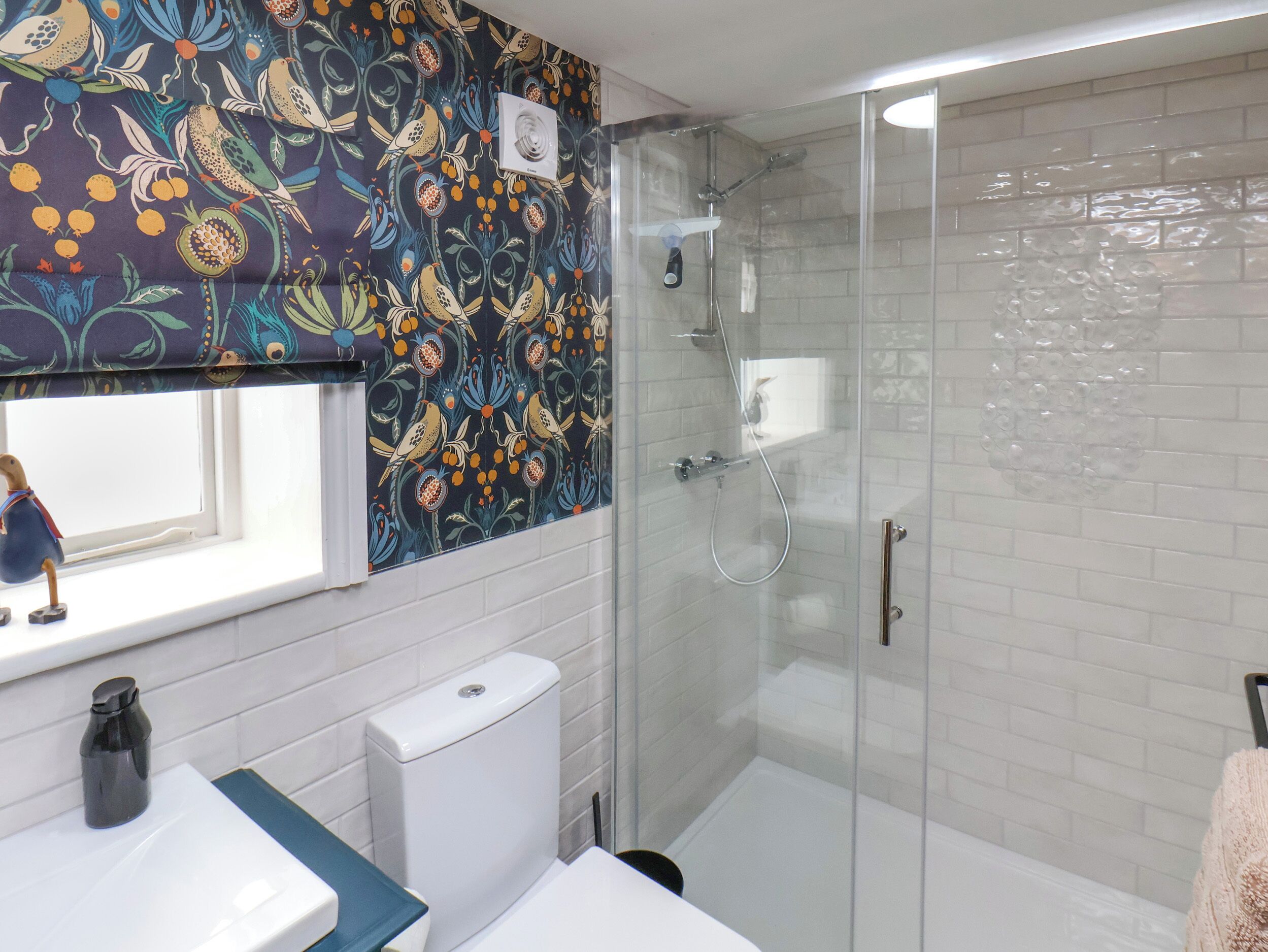 A bathroom with a shower, a toilet, a sink, and a window.