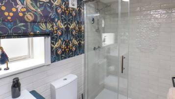 A bathroom with a shower, a toilet, a sink, and a window.