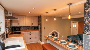 Une cuisine moderne avec des plans de travail en bois, un four encastré et un coin repas comprenant un banc et une table pour deux personnes.