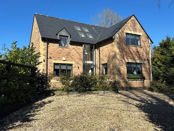 A two-story house with a sloped roof, brick exterior, and a gravel driveway.