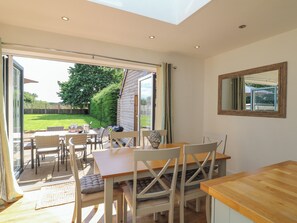 Un coin repas avec une table et des chaises, donnant sur le jardin, et une lucarne au-dessus.