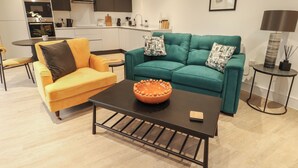 Una sala moderna con un sofá amarillo, un sofá verde azulado y una mesa de centro.