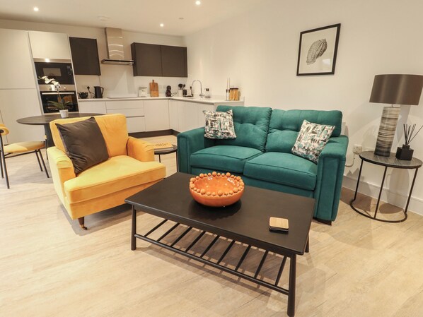 Una sala moderna con un sofá amarillo, un sofá verde azulado y una mesa de centro.