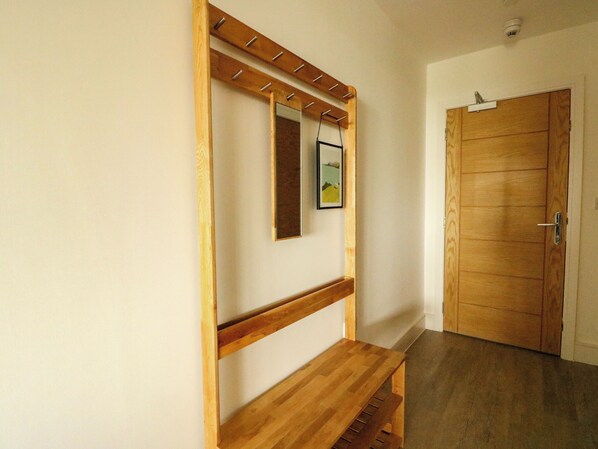 A hallway with a wooden bench, a coat rack, and a door. - Glynllifon 2 (Marianglas)