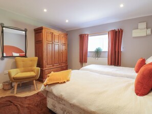 Un dormitorio con dos camas, un armario de madera, una silla y un espejo.