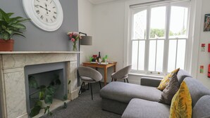 Ein Wohnzimmer mit Kamin, einer Sofagarnitur, einem Esstisch und einem großen Fenster.