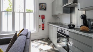 Eine moderne Küche mit großem Fenster, einer Couch und einem an der Wand befestigten Feuerlöscher.