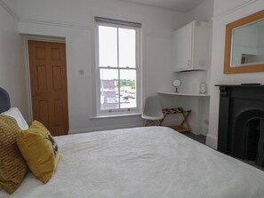 Une chambre à coucher avec un lit, une fenêtre, une chaise, une cheminée et une porte.