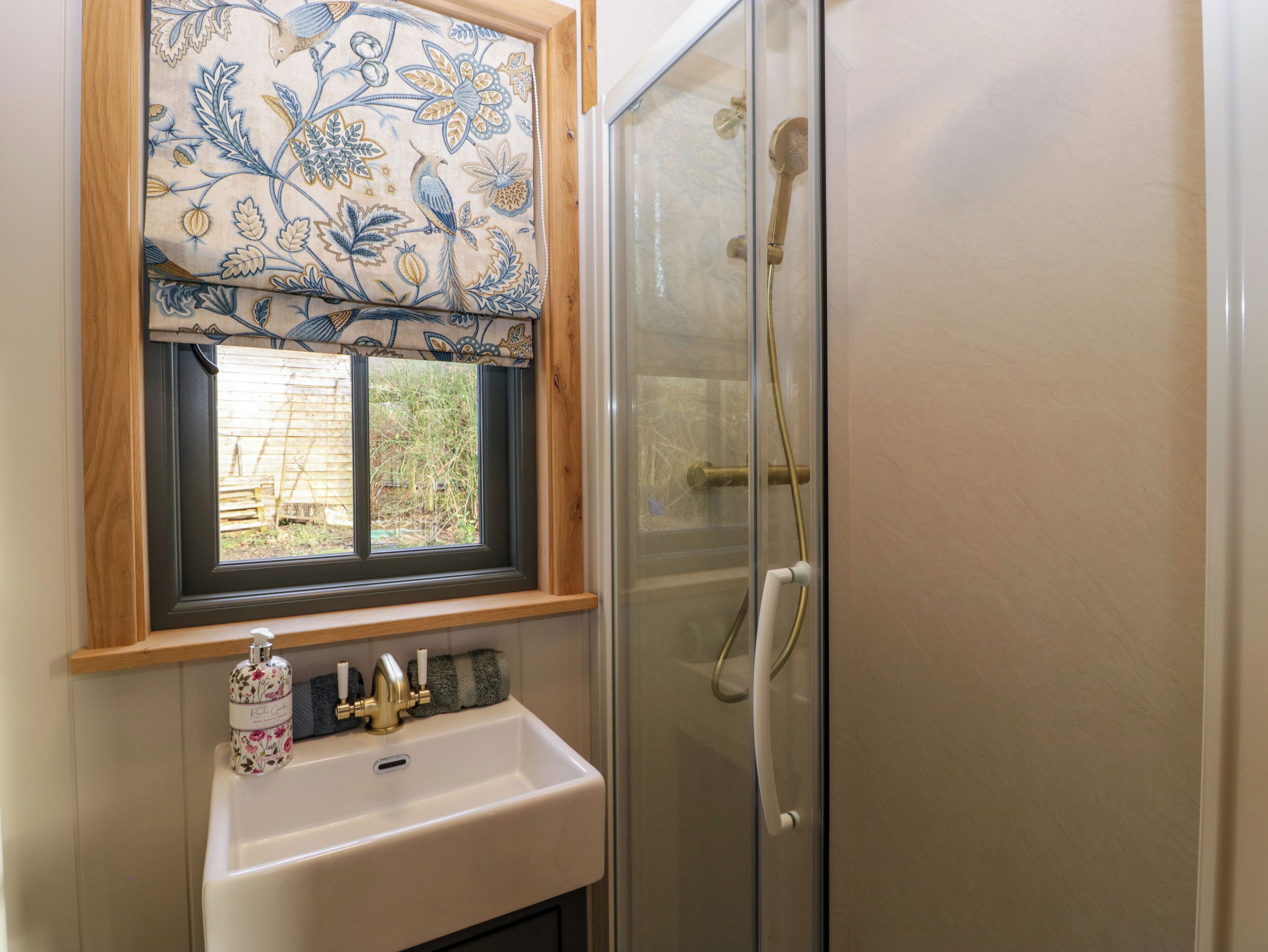 A bathroom with a window, sink, and shower.
