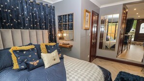 Une chambre avec un grand lit, une table de chevet, un miroir et une vue sur l’extérieur.