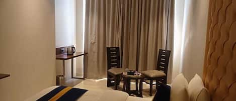 Una habitación de hotel con una cama, dos sillas, una mesita y una cafetera.