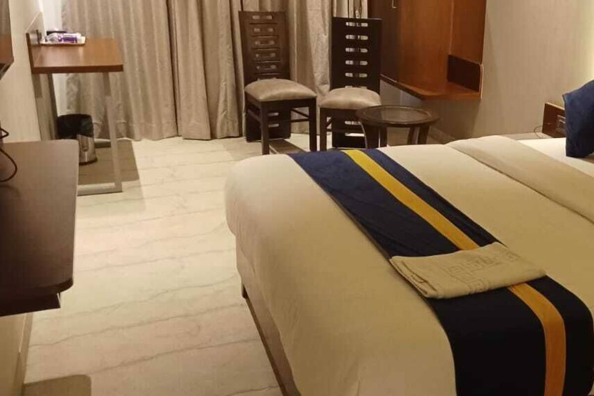A hotel room with a large bed, a desk, and a chair.