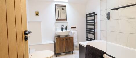 Een moderne badkamer met dakraam, toilet, wastafel en bad.