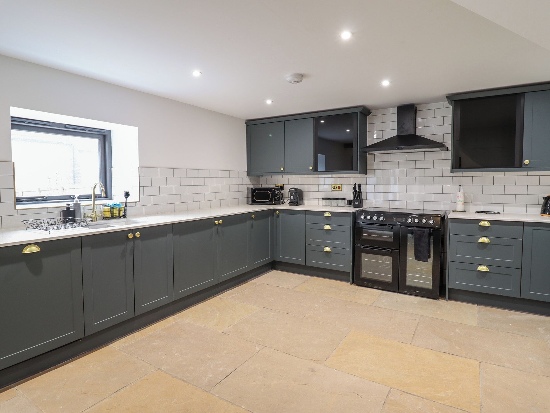 A modern kitchen with grey cabinets, a built-in oven, and a window.
