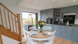 Una cocina moderna con armarios azul claro, una mesa de comedor de madera, sillas blancas y vista al patio exterior.