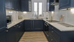 Une cuisine moderne avec des meubles de couleur bleu foncé, un plan de travail blanc et un plancher en bois.