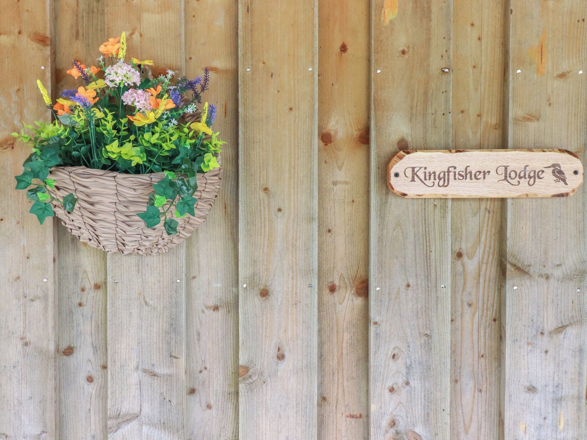 A wooden sign with the text "Kingfisher Lodge" and a bird silhouette.