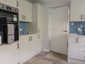 A kitchen with white cabinets, a built-in oven, and a microwave. - Woodstock (Chard)