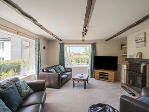 A living room with a fireplace, a sofa, a coffee table, and a television. - Woodstock (Chard)