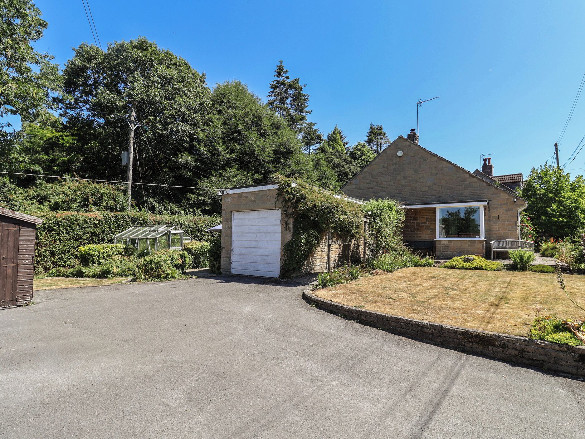 A residential property with a garage, a small shed, and a well-maintained lawn.