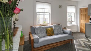 A modern living room with a grey sofa, a wooden coffee table, and a vase of flowers. - Flat 4 - Hengistbury (Bournemouth)