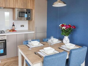 A modern kitchen with a microwave, wine bottle, and glasses on the counter. - Juniper Lodge (Whitby)