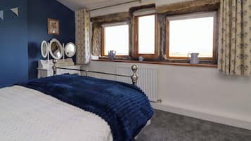Un dormitorio con cama, cómoda, espejo y ventana con cortinas.