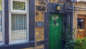 Ein Cottage mit grüner Tür, einem Fenster und einem Schild, das die Nummer 17 anzeigt, Pike View Cottage.