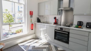 A modern kitchen with white cabinets, stainless steel appliances, and a herringbone-patterned floor. - Flat 3 - Muderford (Bournemouth)