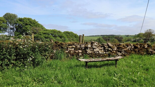 A stone wall, a bench, and a rural landscape with trees and a clear sky. - Willow Lodge (Whitby)