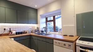 Een moderne keuken met een houten aanrecht, een vaatwasser, een oven en een raam dat voor natuurlijk licht zorgt.