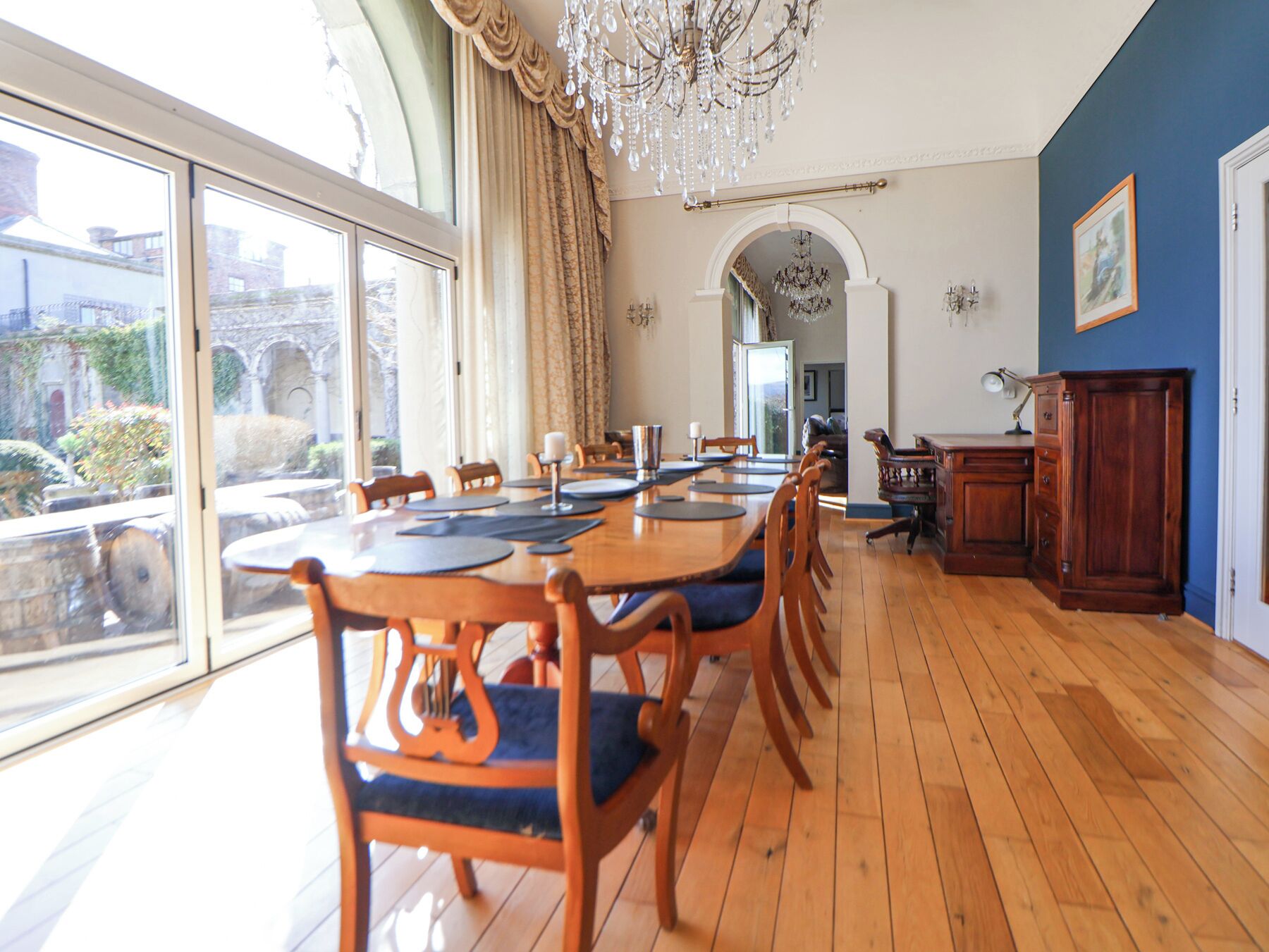 A dining area with a long wooden table, chairs, and a chandelier.