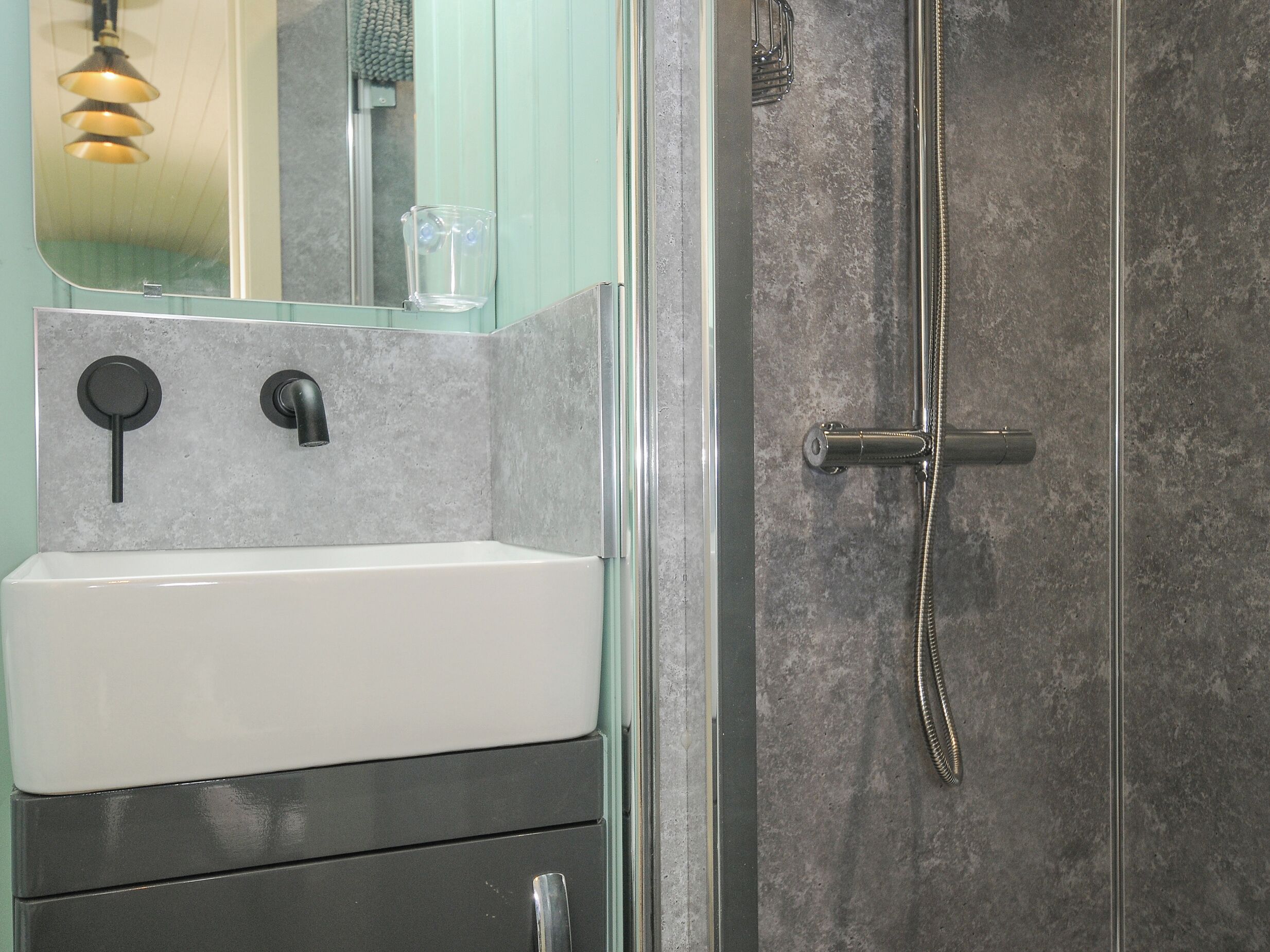 A bathroom with a white sink, a mirror, and a shower with a glass door.