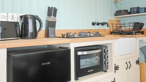 Une cuisine compacte équipée d’un lave-vaisselle encastré, d’une bouilloire électrique noire, d’un grille-pain et d’un four encastré.