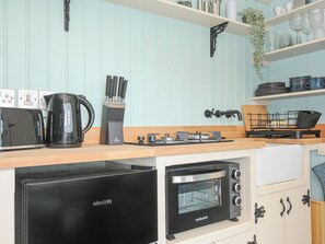 Een koelkast, een broodrooster, kookgerei, borden en bestek