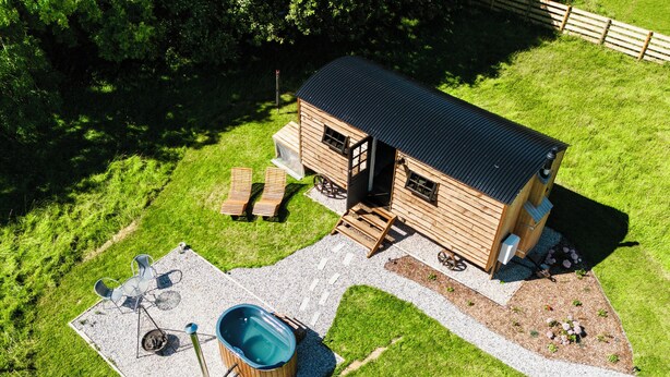 Une cabane en bois dotée d’un bain à remous, d’un espace salon extérieur et d’une terrasse en gravier.