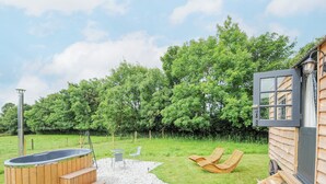 Une cabane en bois dotée d’un bain à remous, d’un espace extérieur aménagé et d’un chemin de gravier.