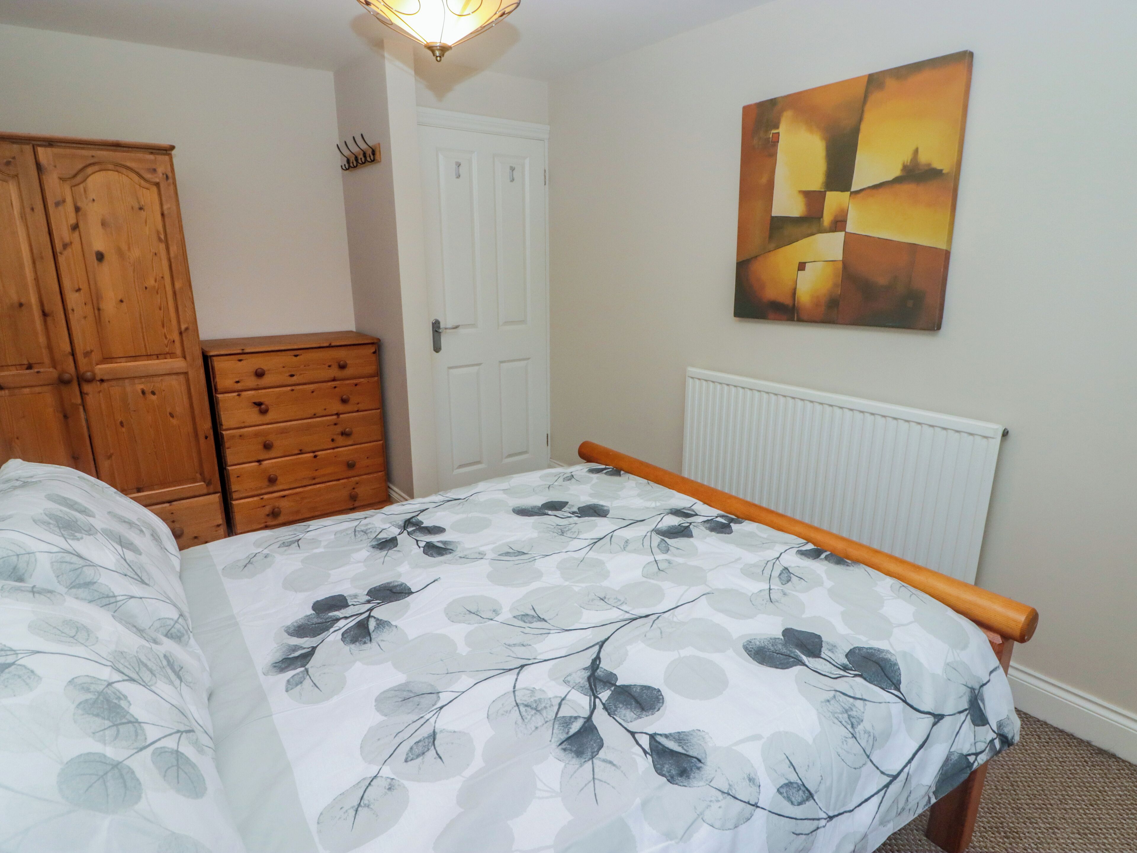 Une chambre à coucher avec un lit, une commode en bois et un radiateur.