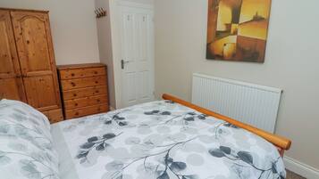 Une chambre à coucher avec un lit, une commode en bois et un radiateur.