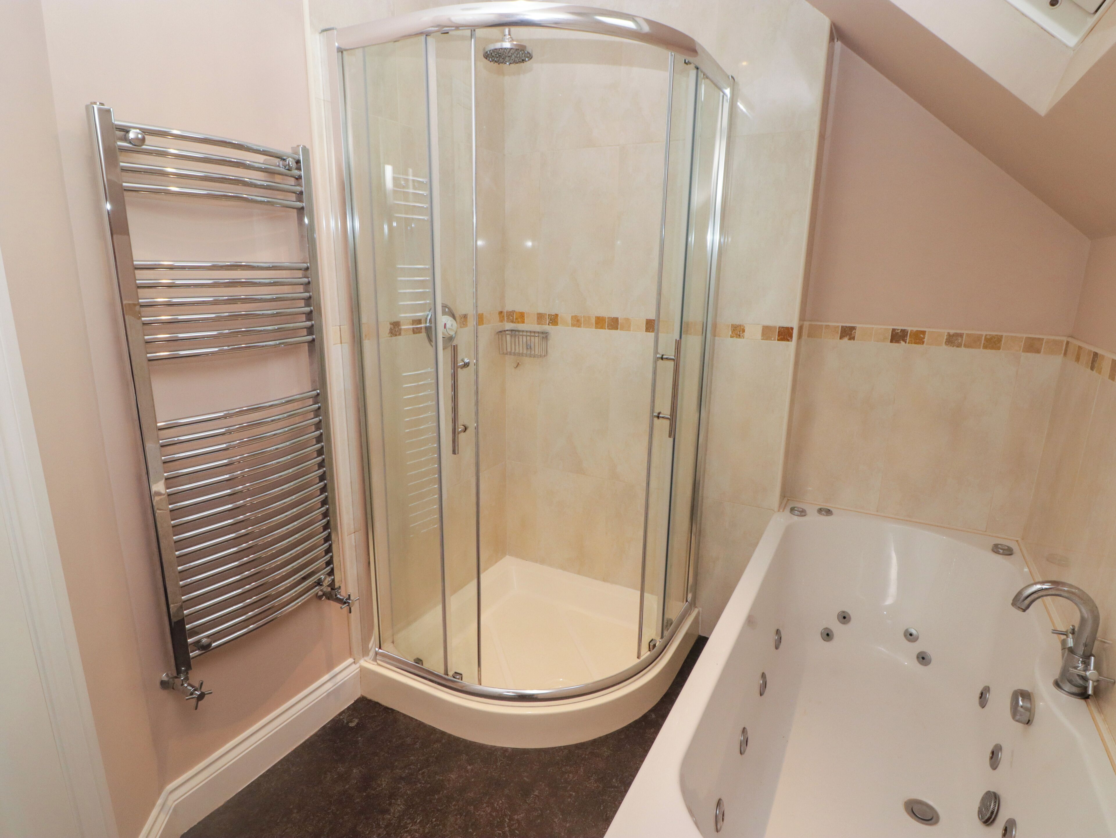 A modern bathroom with a glass-enclosed shower, a separate bathtub, and a towel rack.