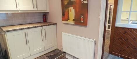 A kitchen with white cabinets, a marble countertop, and a radiator.