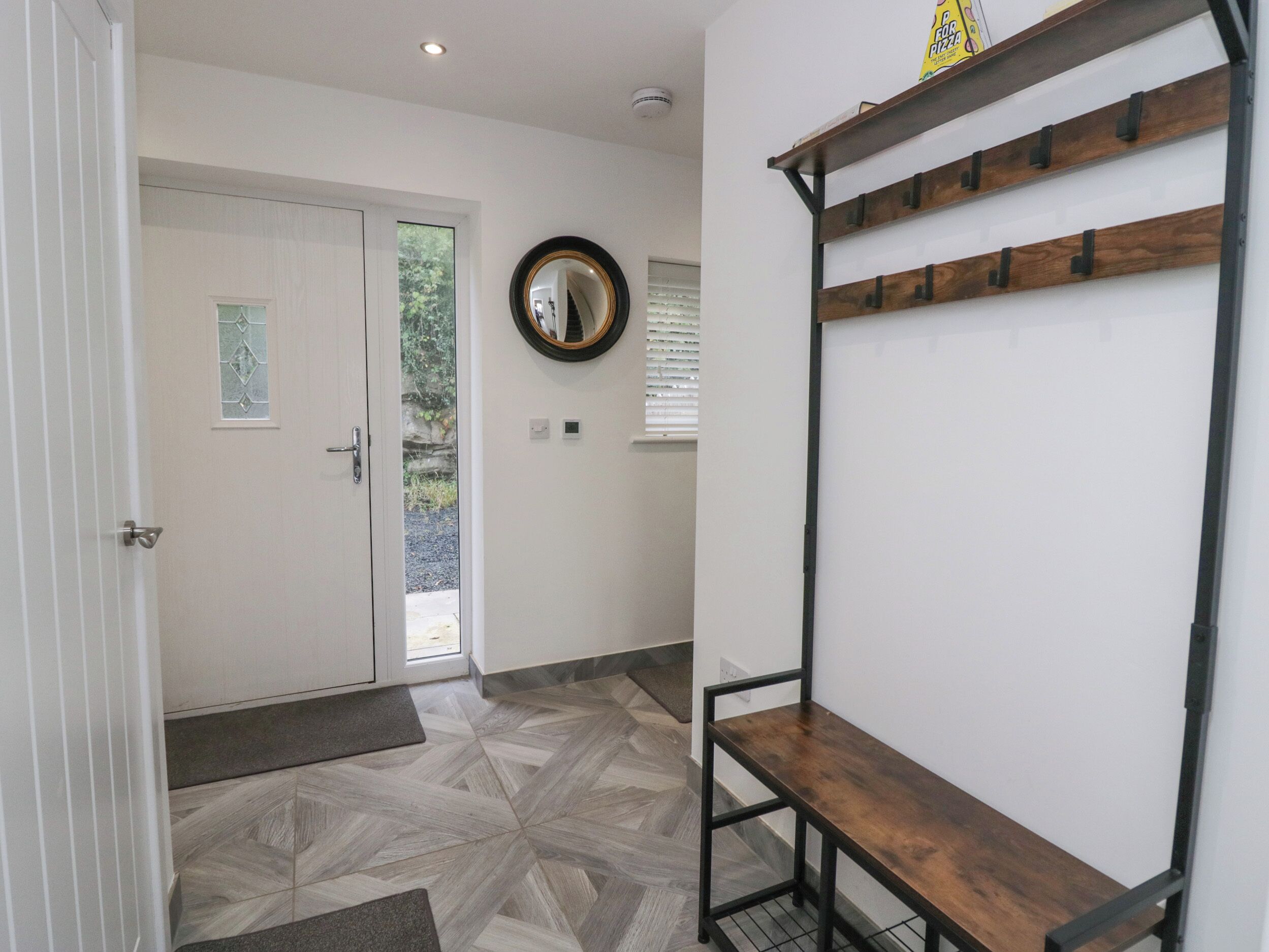 A hallway with a wooden bench, a door with a glass window, and a mirror on the wall.