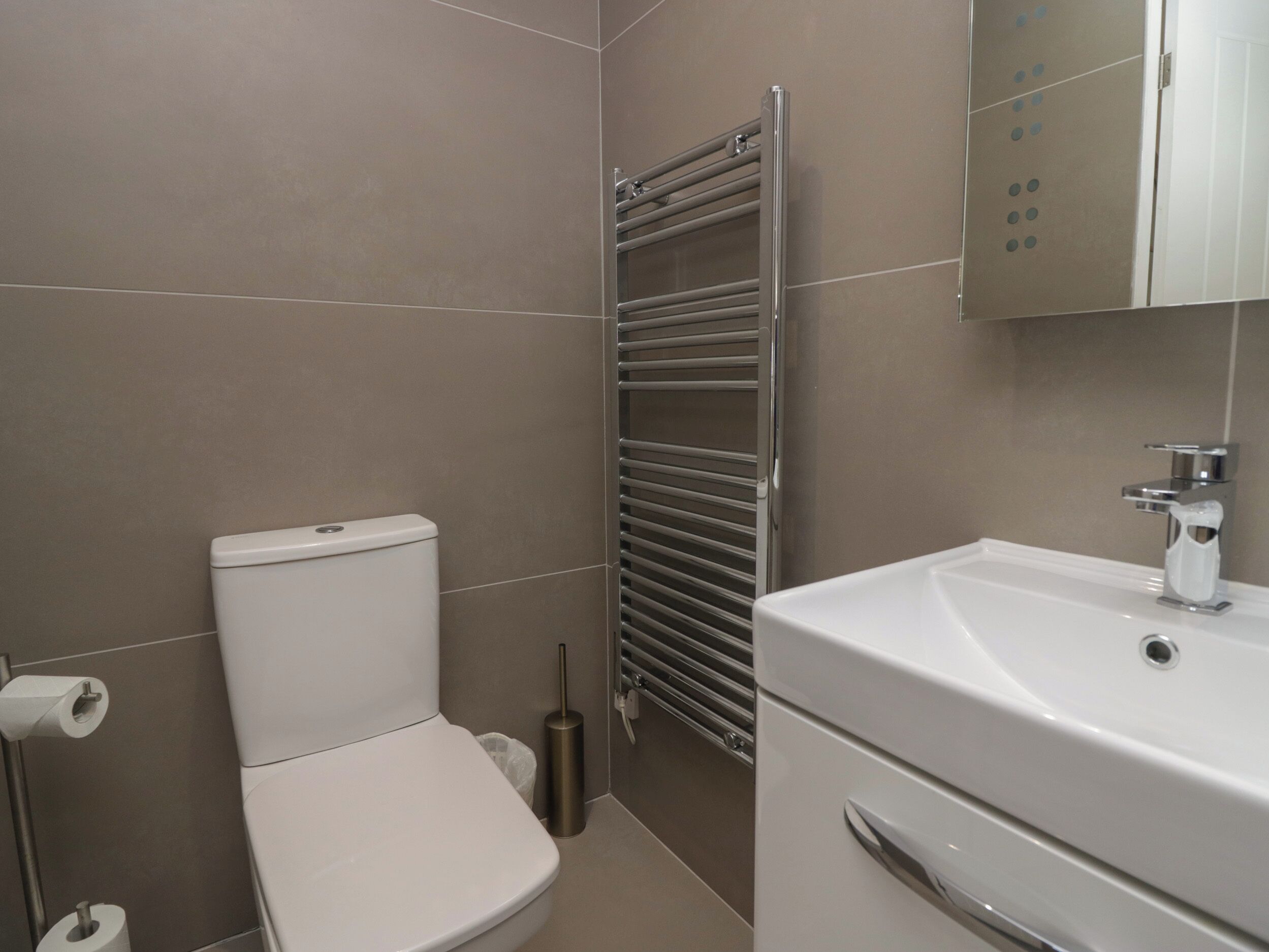 Un baño con inodoro, lavamanos y toallero.