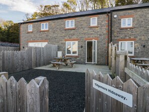 Ein Steinhaus mit mehreren Fenstern und einem Holzzaun, auf dem 'Edgemere Hideaway' steht.