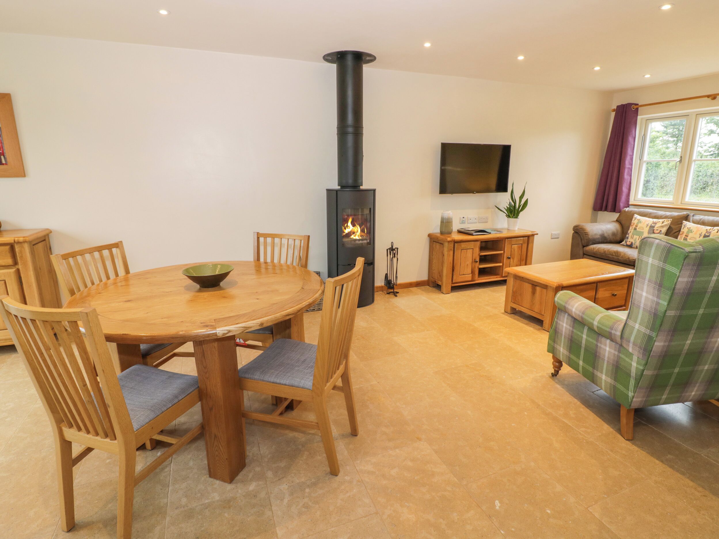 Una sala de estar acogedora con una mesa de comedor de madera, sillas, un sofá y una chimenea.