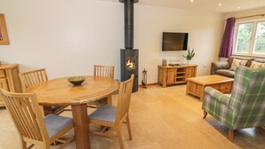 Een gezellige woonkamer met een houten eettafel, stoelen, een bank en een open haard.
