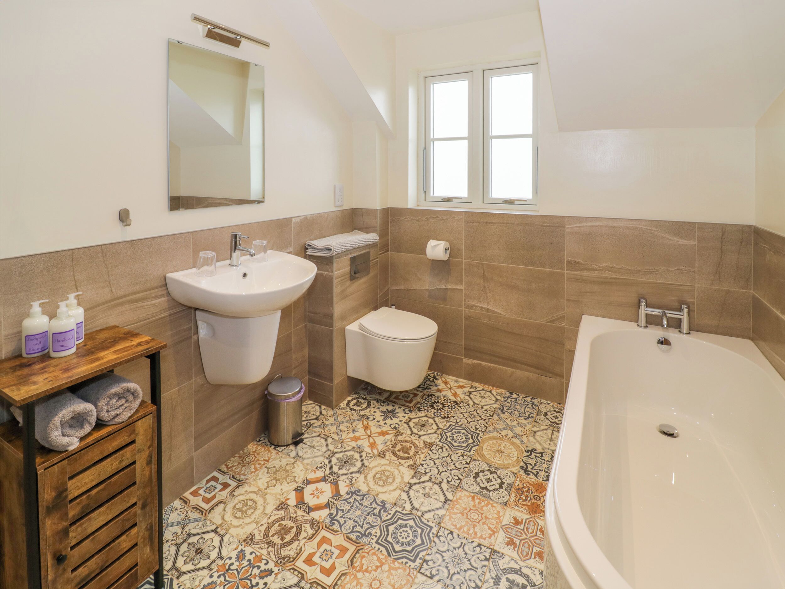 A bathroom with a sink, toilet, and bathtub. There is a window above the toilet and a mirror above the sink.
