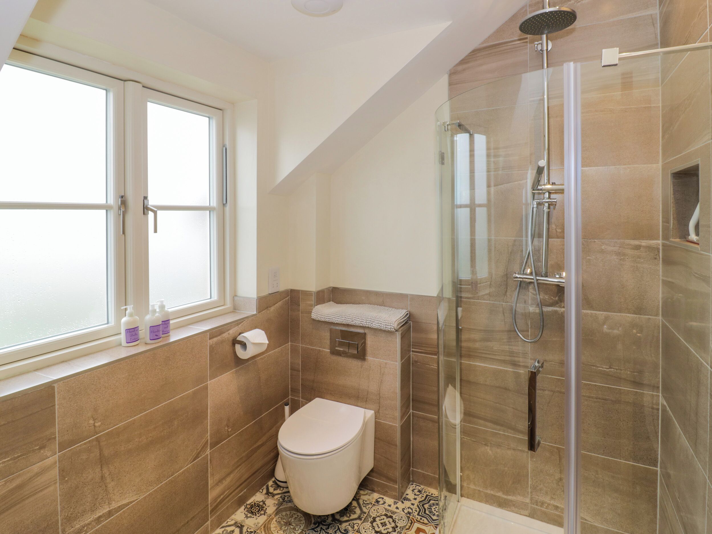 A bathroom with a toilet, a shower, and a window.