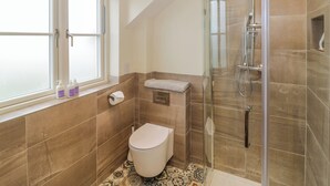 Une salle de bain avec des toilettes, une douche et une fenêtre.