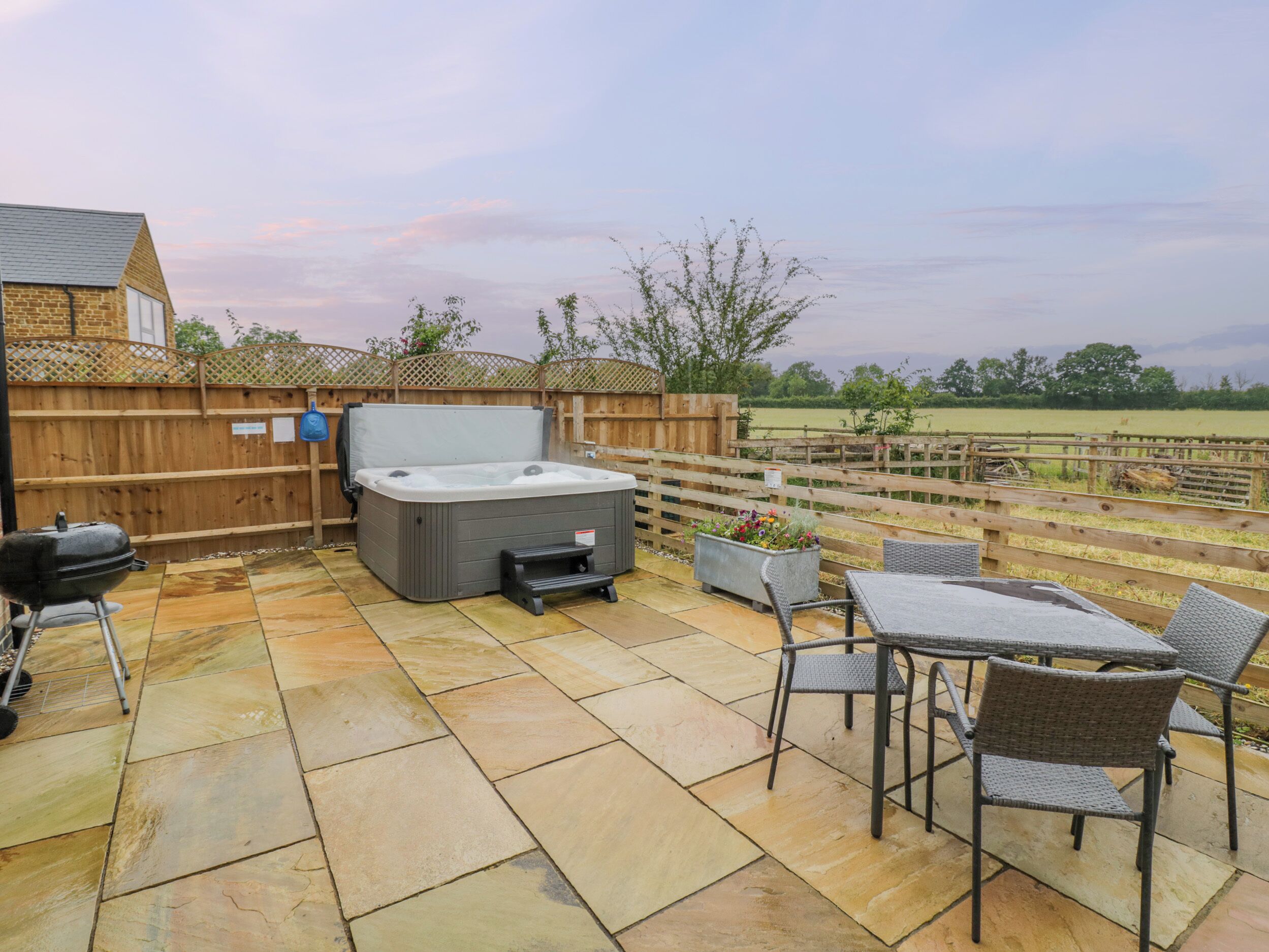 A patio with a hot tub, a grill, and outdoor furniture.
